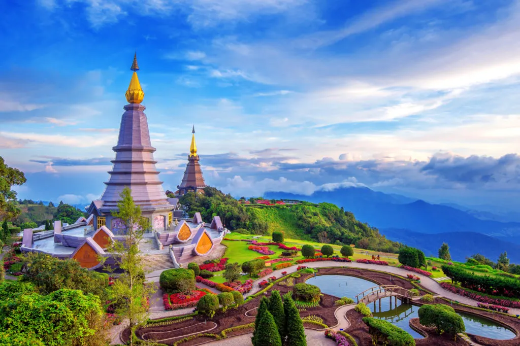 Scenic view of the Grand Palace in Bangkok, Thailand, showcasing the ornate golden rooftops, traditional Thai architecture, and vibrant temple structures under a bright blue sky.