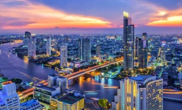 Scenic view of Bangkok city skyline with buildings, lights, and sunset