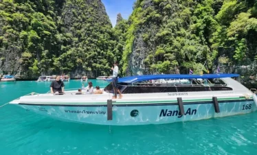 Speedboat cruising on clear turquoise waters near limestone islands in Krabi, Thailand
