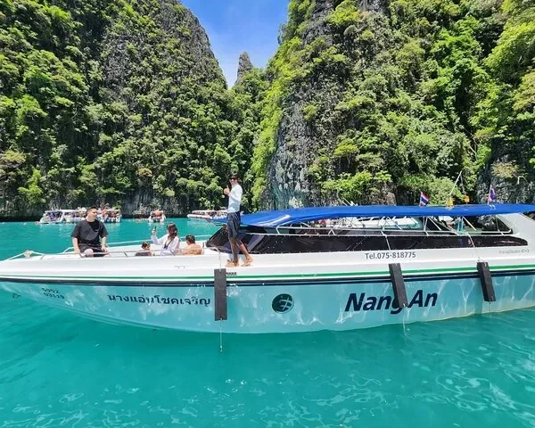 Speedboat cruising on clear turquoise waters near limestone islands in Krabi, Thailand