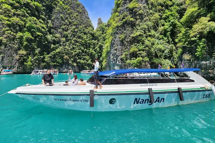 Speedboat cruising on clear turquoise waters near limestone islands in Krabi, Thailand