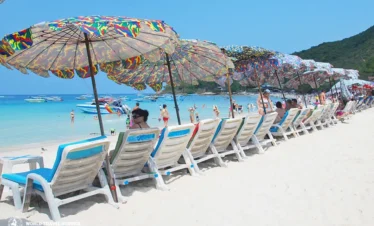 ourists relaxing under umbrellas and enjoying beach views at Coral Island (Koh Larn)