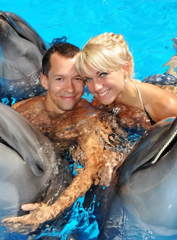 Tourist posing with a dolphin inside the water at Dolphin Show Phuket