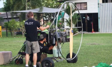 Pilot and guest preparing for paramotor flight with helmet and harness