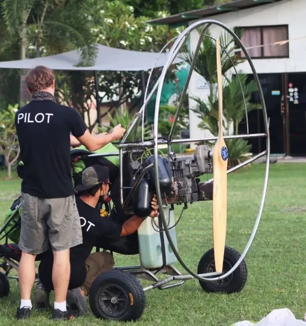 Pilot and guest preparing for paramotor flight with helmet and harness