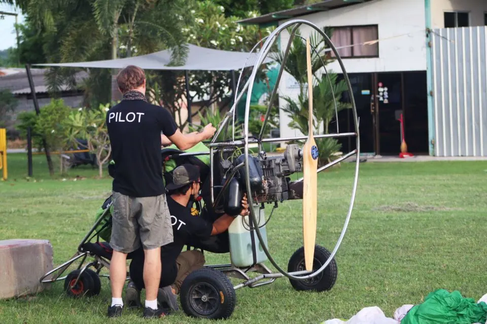 Pilot and guest preparing for paramotor flight with helmet and harness