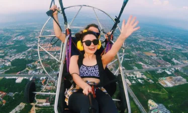 Tourist smiling while flying with 4K video camera on paramotor