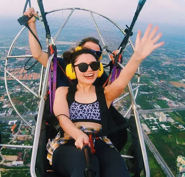 Tourist smiling while flying with 4K video camera on paramotor