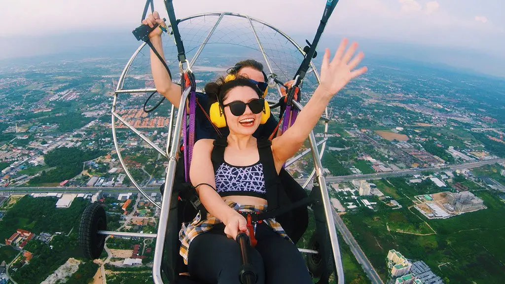 Tourist smiling while flying with 4K video camera on paramotor