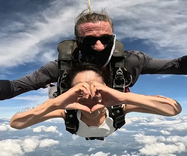 Skydiving passenger and instructor posing mid-air during free-fall over Pattaya