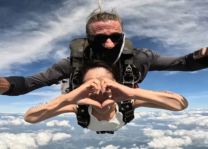 Skydiving passenger and instructor posing mid-air during free-fall over Pattaya