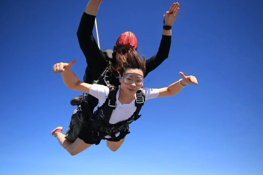 Female passenger and skydiving instructor posing mid-air during free-fall over Pattaya