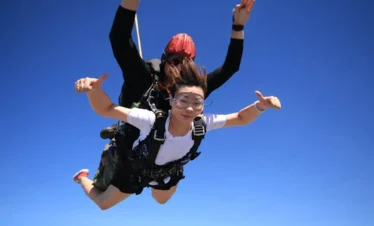 Female passenger and skydiving instructor posing mid-air during free-fall over Pattaya