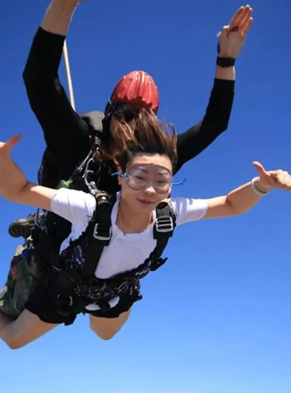 Female passenger and skydiving instructor posing mid-air during free-fall over Pattaya