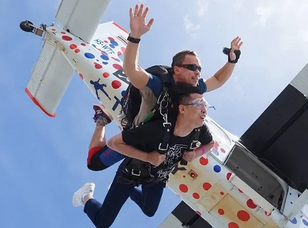 Tandem skydiving jump with instructor and passenger exiting the plane over Pattaya
