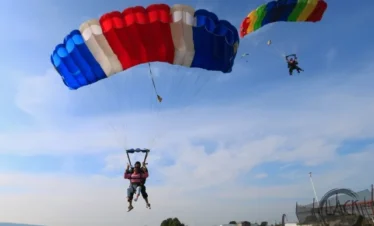 Two tandem parachutes open, descending side by side for landing in Pattaya