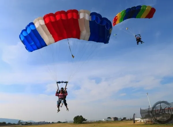 Two tandem parachutes open, descending side by side for landing in Pattaya