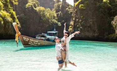 UK tourists enjoying a sunset beach in Thailand with longtail boats in view