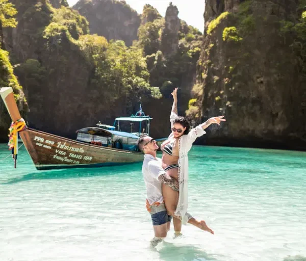 UK tourists enjoying a sunset beach in Thailand with longtail boats in view