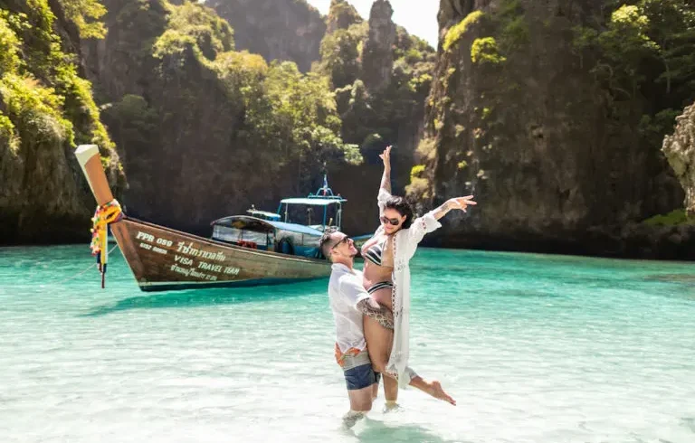 UK tourists enjoying a sunset beach in Thailand with longtail boats in view