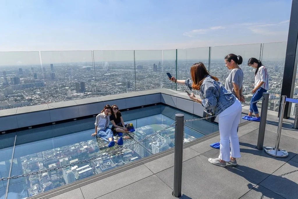 Visitors enjoying the thrilling glass tray experience at Mahanakhon Skywalk