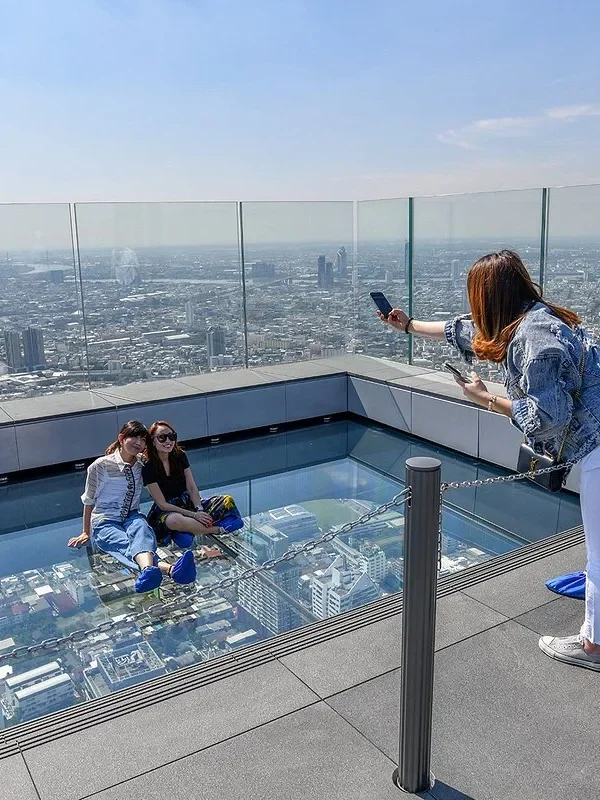 Visitors enjoying the thrilling glass tray experience at Mahanakhon Skywalk