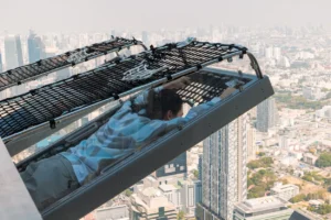 Traveler enjoying the Mahanakhon I‑Tilt ride with panoramic view of Bangkok at sunset