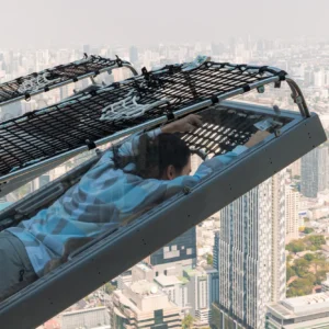 Traveler enjoying the Mahanakhon I‑Tilt ride with panoramic view of Bangkok at sunset