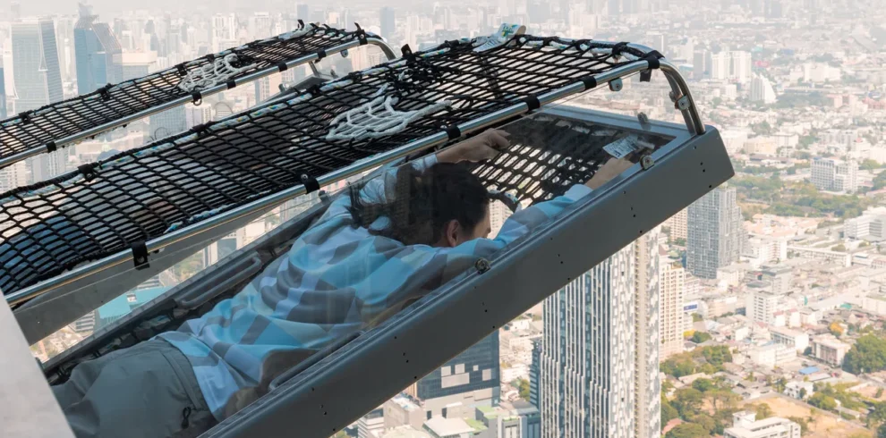 Traveler enjoying the Mahanakhon I‑Tilt ride with panoramic view of Bangkok at sunset