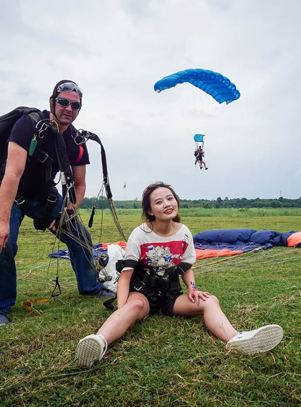 Tandem skydiver and instructor posing after landing in Khao Yai.